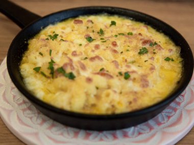 Fırında makarna ve peynir, dökme demir tavada, restoran konforlu yemek fotoğrafçılığı, ahşap masanın önünü kapat.