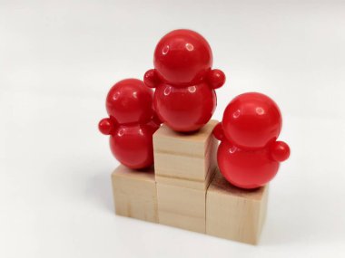 Podyum bloklarında üç rakamlı plastik bebeklerin minyatürleri bir yarışma veya başarı senaryosunda sıralama pozisyonlarını temsil etmektedir.