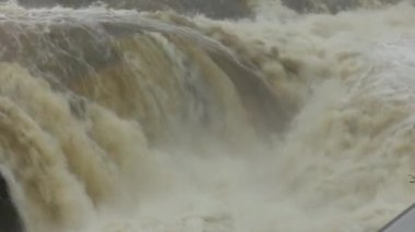 Şiddetli yağmurun ardından hızlı ve çalkantılı nehir akışı. Şiddetli yağış sonrasında akıntının hızını ve türbülansını artıran güçlü bir su dalgası nehrin aşağısına hücum eder. Kabarık akıntı güç ile çalkalanır ve beyaz köpük oluşturur.