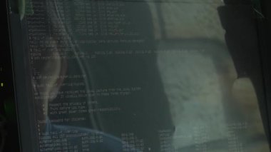 IT donanımlarıyla çevrili bir sunucu odasındaki bir bilgisayarda yazıcı kodu. Yazılım geliştirme, siber güvenlik, sistem yönetimi ve modern dijital altyapı için ideal.