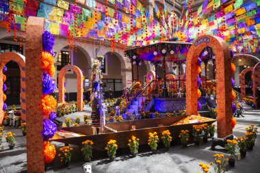 Meksika 'da Ölüler Günü' nde sunaklar, adaklar ve madalyalar. Merhumu onurlandıran unsurlardan oluşan bir derleme. İspanyol ve Katolik geleneklerini birleştirip yaşayanlarla ölülerin bir arada olduğu bir festival alanı yaratıyorlar..