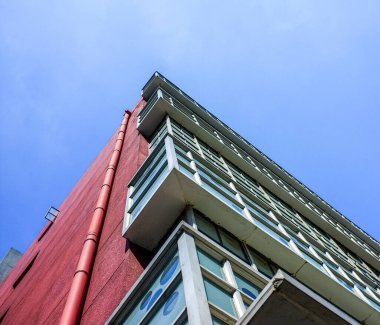 Açık mavi gökyüzüne karşı bir binanın dış köşesine bakıyorum. Görüntü, kornişler, pencereler ve çatı çizgileri gibi mimari unsurları vurguluyor. Bu konsept şehir tasarımı ve gayrimenkul taşır. Otantik gerçek fotoğrafçılık.