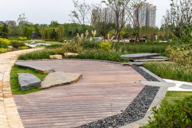 Gömülü taş levhalar ve süs otları olan ahşap bir güverte manzarası. Görüntü açık hava eğlencesi ve karışık malzeme tasarımı sunuyor. Yüksek kaliteli gerçek fotoğrafçılık..