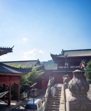 HUANGMEI, CHINA - AUGUST 10, 2016: A view of the stone staircase and courtyard of the historic Sizu Temple (Fourth Ancestor Temple). A monk walks in the distance amidst traditional architecture.
