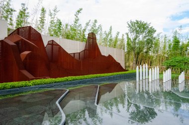 HANGZHOU, ÇİN - 3 Temmuz 2017: Paslı Corten çelik levhalarının soyut dağ şekillerine kesilen perspektif görüntüsü. Sığ bir su havuzunda, arkasında bambu olan bu tesis geleneksel Çin topraklarının modern bir yorumunu temsil ediyor.