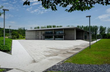 HANGZHOU, ÇİN - 06 Temmuz 2017: Yeşil çimenler ve ağaçların arasında yer alan Liangzhu Sanat Merkezi 'nin geniş bir manzara görüntüsü. Gri beton bina mavi gökyüzünün altındaki doğal çevreyle çelişiyor..