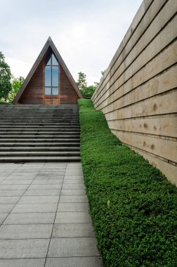 HANGZHOU, ÇİN - 06 Temmuz 2017: Meilizhou Kilisesi 'nin merdiven girişinde dokuma taşlı istinat duvarı ve manikürlü yeşil çit astarlı çit manzarası. Geometrik çizgiler gözü üçgen şapele yönlendiriyor..