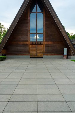 HANGZHOU, CHINA - JULY 06, 2017: Vertical close-up view of the front facade and entrance of Meilizhou Church. The image highlights the distinctive triangular wooden shape, large glass window, and stone paved plaza.