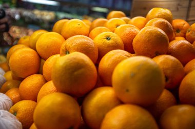 Bir markette ya da markette taze portakal yığınının yakın görüntüsü. Dokulu, parlak turuncu turuncu turunçgil meyveleri yiyecek ve beslenme kavramları için uygun tazelik, sağlık ve bolluk taşır..