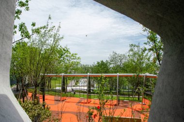 HANGZHOU, ÇİN - 3 Temmuz 2017: Modern bir iskan parkında turuncu kauçuk bir oyun alanı yüzeyine doğru eğimli beton mimari bir açıklıktan bakan bir manzara.
