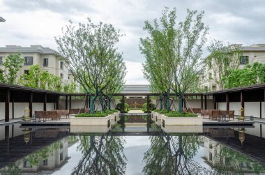 HANGZHOU, ÇİN - 4 Temmuz 2017: lüks bir konutun geniş simetrik manzarası. Büyük bir su havuzu yeşil ağaçları ve çevresindeki koridorları yansıtarak toplumda barışçıl bir Zen atmosferi yaratır..