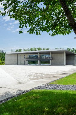 HANGZHOU, ÇİN - 6 Temmuz 2017: Liangzhu Sanat Merkezi 'ne dikey bir bakış açısı önplanda yeşil ağaç yaprakları ile çerçevelenmiş, doğa ve Tadao Ando mimarisi arasındaki uyumu vurguluyor.