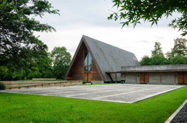HANGZHOU, ÇİN - 06 Temmuz 2017: Yeşil bir manzarada yer alan Meilizhou Kilisesi 'nin geniş görüşü. Görüntü, ağaçlar ve otlarla harmanlanmış modern ahşap binanın tam uzunluğunu yakalıyor..