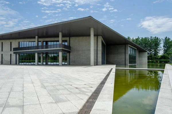 HANGZHOU, ÇİN - 06 Temmuz 2017: Taş kaldırımlı plazanın alçak açısı ve Hangzhou 'daki Liangzhu Sanat Merkezi' nin beton yapısına bitişik bir su havuzu.