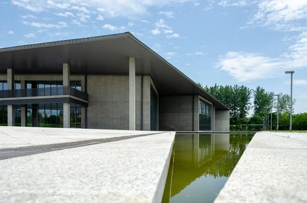 HANGZHOU, ÇİN - Temmuz 06, 2017: Su özelliğinin kenarına yakın çekim açısı ve Liangzhu Sanat Merkezi 'nin modern beton mimarisi mavi gökyüzüne karşı.