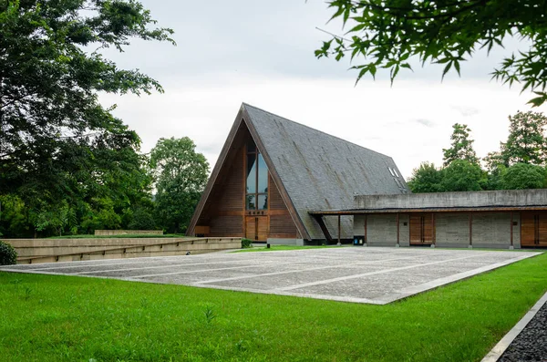 HANGZHOU, ÇİN - 06 Temmuz 2017: Yeşil bir manzarada yer alan Meilizhou Kilisesi 'nin geniş görüşü. Görüntü, ağaçlar ve otlarla harmanlanmış modern ahşap binanın tam uzunluğunu yakalıyor..