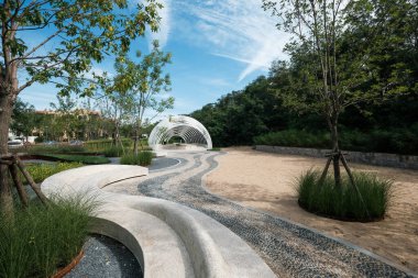 Qinhuangdao, Hebei Eyaleti, Çin - 16 Eylül 2018: Eğri beton banklar ve çakıl yolları içeren gelişmiş bir modern manzara tasarımı Aranya yerleşim bölgesinde yemyeşil ağaçlarla çevrili.