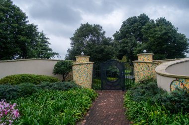 Şangay, Çin - Aralık 04, 2018 Şangay Disneyland Parkı 'ndaki renkli mozaik fayanslar ve yemyeşil yeşilliklerle kıvrımlı bir dekoratif duvara açılan siyah demir bir kapı..