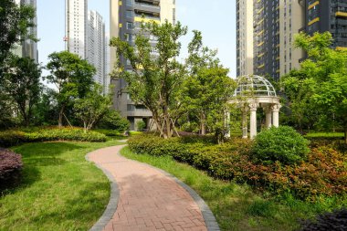 Yeşil bir çimenliği kesen dolambaçlı bir tuğla yolu, gözleri ağaçlar ve apartmanlarla çevrili klasik bir taş çardağa götürüyor..