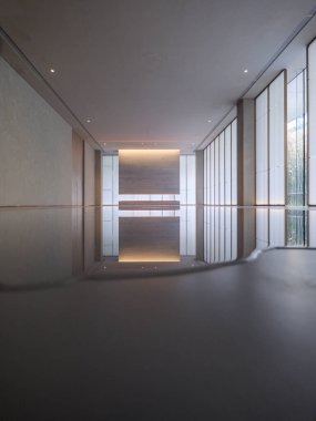 Modern, minimalist bir koridorun dikey iç görünüşü. Yüzeyde sığ bir yansıma havuzu var. Duvarları yansıtıyor ve ışıklandırıyor..