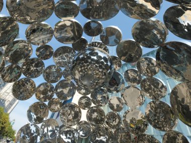 Düşük açılı soyut fotoğrafçılık gökyüzünü yansıtan sayısız parlatılmış paslanmaz çelik kürelerden oluşan büyük bir halk sanatı kurulumuna bakıyor..