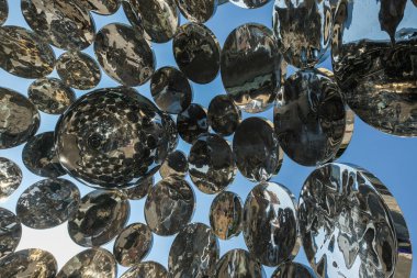 Geniş bir sanat yapısına bağlı çoklu krom kürelerin detaylı çekimi, metalik yüzeyi vurguluyor ve yansımaları bozuyor..