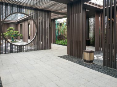 Geleneksel Zen estetiğinden esinlenilmiş çağdaş bir dış avlu tasarımı, dairesel ay kapısı, ahşap çıtalar ve taş teras..