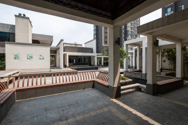 Ahşap oturma alanları, taş yollar ve su özelliklerinin yer aldığı, modern yapı ile birleştirilmiş panoramik bir yerleşim alanı..