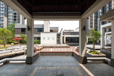 Çağdaş apartman kompleksleri ve minimalist peyzaj ile çevrili simetrik bir avluya bakan bir taraça manzarası.