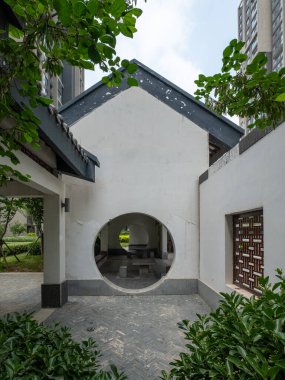 Dikey bir çekim, dairesel ay kapısı olan zarif beyaz duvarı ve huzurlu bir bahçede geleneksel çatı saçaklarını yakalıyor..