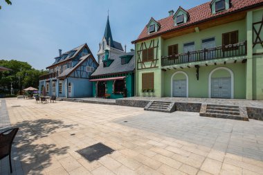 Yarı ahşap cepheler ve kemerli pencereler de dahil olmak üzere geleneksel Avrupa mimari tarzlarının yer aldığı temalı bir turizm kasabasının sokak düzeyinde bir perspektifi.