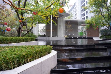 Manikürlü çitlerin, su kanallarının ve ağaçların yer aldığı canlı yeşil bir açık alan doğanın ve modern tasarımın uyumlu bir karışımını oluşturuyor. Görüntü canlılığı, büyümeyi, barışı ve lüks yaşamı aktarıyor. Sığ d ile yüksek kaliteli gerçek fotoğrafçılık