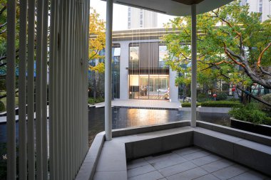 Hala yansıtan bir havuzun yanında yer alan modern bir pavyon yapısı, verimli bir mimari manzara içinde yer alıyor. Görüntü meditasyonu, dinginliği, sükuneti ve mimari güzelliği aktarıyor. Sığ alan derinliğine sahip yüksek kaliteli gerçek fotoğrafçılık.