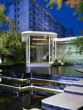 Modern bahçe köşkünün çarpıcı uzun perspektifi akşam gökyüzünün altındaki karanlık bir havuza mükemmel bir şekilde yansıyor. Görüntü, mimari hassasiyet, lüks, dinginlik ve derin dinginlik taşır. Sığ alan derinliğine sahip yüksek kaliteli gerçek fotoğrafçılık