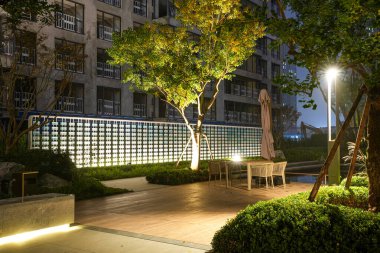 Geceleri verimli, aydınlık bir bahçeye kurulmuş modern mobilyalarla dolu rahat bir bahçe. Görüntü, sosyal konfor, modern lüks, sükunet ve huzurlu bir akşam hayatı sunuyor. Sığ derinlikli yüksek kaliteli gerçek fotoğrafçılık