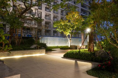 Yumuşak zemin aydınlatması ve geceleri modern arka ışıklandırma duvarı olan huzurlu bir bahçe yolu. Resim, akşam eğlencesi, yapısal güzellik, dinginlik ve son model peyzaj tasarımı sunuyor. Sığ alan derinliğine sahip yüksek kaliteli gerçek fotoğrafçılık.