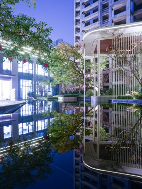 Modern mimari çizgilerin ve manzaralı bir bahçede bol miktarda su yansımalarının olduğu büyüleyici bir gece sahnesi. Görüntü görsel derinlik, barışçıl lüks ve modern tasarım uyumu taşır. Sığ alan derinliğine sahip yüksek kaliteli gerçek fotoğrafçılık