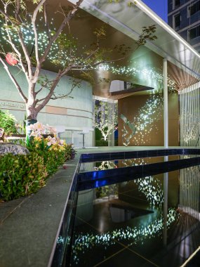 Modern yapının kesişimine, dekoratif dokulara ve yumuşak bahçe ışıklarına odaklanan yakın çekim. Görüntü karmaşıklık, mimari entelektüellik ve akşam barışı içeriyor. Sığ derinliğe sahip yüksek kaliteli gerçek fotoğrafçılık