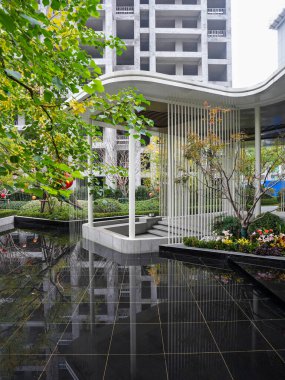 Canlı yeşilliklerle çevrili bir yansıtma havuzunu çerçeveleyen modern bir pavyonun barışçıl mimari görüşü. Görüntü uyumu, lüksü, sükuneti ve doğal güzelliği temsil eder. Sığ alan derinliğine sahip yüksek kaliteli gerçek fotoğrafçılık.