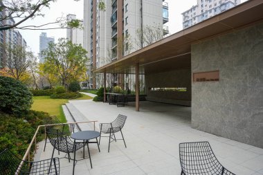 Üst düzey bir avluda siyah demir masaları ve sandalyeleri olan modern minimalist açık hava köşkü. İmaj, rahatlamayı ve modern toplumda yaşamayı ifade ediyor. Doğal ışıklandırmalı yüksek kaliteli gerçek fotoğrafçılık.