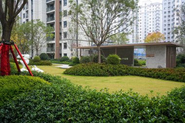 Geniş yeşil çimenler ve güneş ışığı altında çalılar. Huzurlu bir toplum ortamında modern bir pavyon. Görüntü ekolojik sağlık ve yüksek kaliteli yaşam taşıyor. Doğal ışıklandırmalı yüksek kaliteli gerçek fotoğrafçılık.