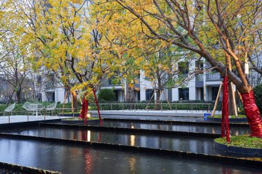Sonbahar ağaçlarını yansıtan çok katlı manzara suları ve alacakaranlıktaki üst düzey bir halk avlusunda sıcak ışıklar. Görüntü zarif bir peyzaj ve huzurlu bir yaşam sunuyor. Doğal ışıklandırmalı yüksek kaliteli gerçek fotoğrafçılık.