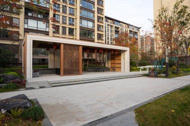 Modern tasarımı geleneksel tahta levhalar ve kırmızı fenerlerle harmanlayan zarif bir topluluk pavyonu. Görüntü kültürel füzyon ve özel yaşam tarzını aktarıyor. Doğal ışıklandırmalı yüksek kaliteli gerçek fotoğrafçılık.