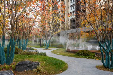 Yapay bir sis, küçük bir çeşme, dolambaçlı yollar ve canlı sonbahar ağaçlarıyla dolu sakin bir avlu. Görüntü doğal bir vaha ve ahenkli bir şehir yaşamını taşır. Doğal ışıklandırmalı yüksek kaliteli gerçek fotoğrafçılık.