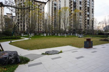 Modern taş kaldırımlı plaza, huzurlu bir toplum ortamında dekoratif taşları olan büyük manikürlü yeşil bir çimenliğe dönüşüyor. Görüntü şehir vahasını ve açık yeşil alanı taşır. Doğal ışıklandırmalı yüksek kaliteli gerçek fotoğrafçılık.