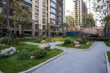 Huzurlu bir topluluktaki güzel manzaralı yeşil bahçeden geçen farklı çakıl ve asfalt bir yol. Görüntü, uyumlu bir yaşam ve huzurlu bir açık hava ortamı sunuyor. Doğal ışıklandırmalı yüksek kaliteli gerçek fotoğrafçılık.