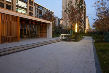 Alacakaranlıkta sakin bir halk bahçesindeki zarif ahşap bir köşkün yanındaki sıcak lamba direkleriyle aydınlatılmış taş kaldırım yolu. Görüntü, kentsel sükunet ve güvenli bir ortam sağlıyor. Doğal ışıklandırmalı yüksek kaliteli gerçek fotoğrafçılık.