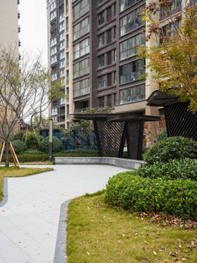 Çağdaş karanlık gölge yapılara doğru yeşil çimlerden geçen dolambaçlı bir yol huzurlu bir toplum avlusunda. Görüntü, zarif bir açık hava yaşam ve şık bir peyzaj mimarisi sunuyor. Yüksek kaliteli gerçek fotoğrafçılık