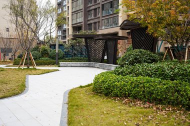 Yeşil çimlerle çevrili geniş kıvrımlı taş kaldırım ve birinci sınıf bir yerleşim bölgesinde çağdaş dinlenme barınakları. Görüntü, birinci sınıf bir toplum ve geniş bir açık hava ortamı sağlıyor. Yüksek kaliteli gerçek fotoğrafçılık.