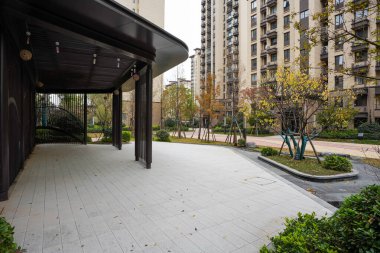 Modern bir koyu metal gölgelik yapının altından sakin bir avludaki asfalt kaldırıma ve apartmanlara bakıyor. Görüntü, modern toplumu, yaşayan ve barışçıl bir çevreye taşır. Natura ile yüksek kaliteli gerçek fotoğrafçılık